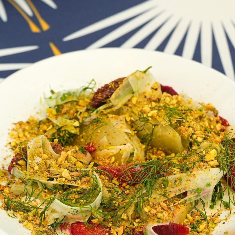 Fennel and blood orange salad with chopped pistachios and fresh dill on a white plate.