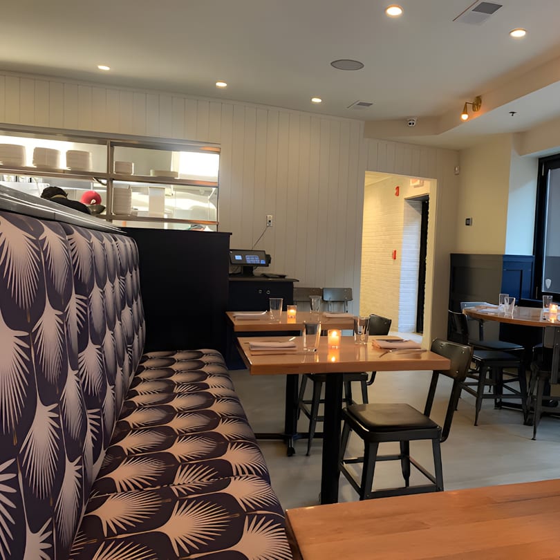 Interior of Redcrest Kitchen with patterned booth seating, wooden tables, and an open kitchen pass-through.