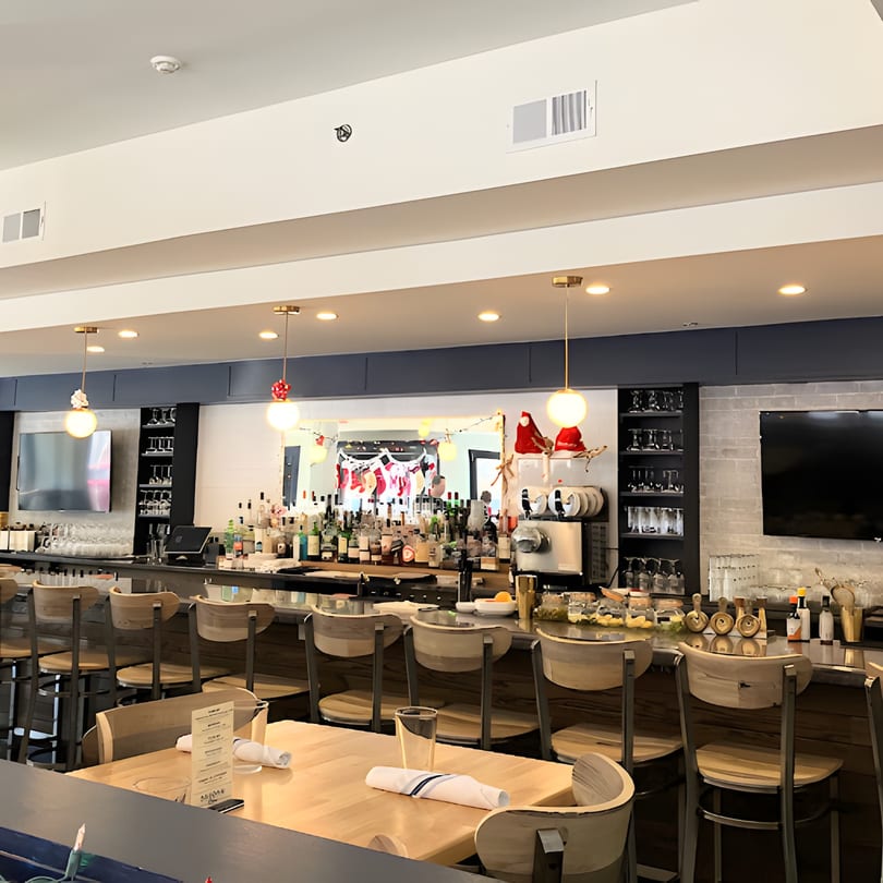The Redcrest Kitchen bar area with stools, bottles, and holiday decorations reflected in a mirror.